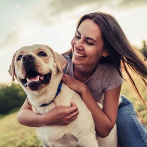 Attractive young woman with labrador outdoors. Woman on a green grass with dog labrador retriever.